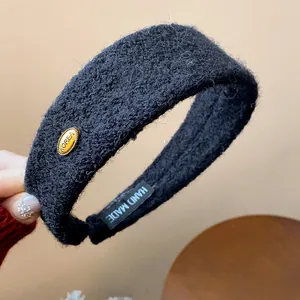 Detailed view of a black flocked wide headband with a gold Korea tag and handmade label