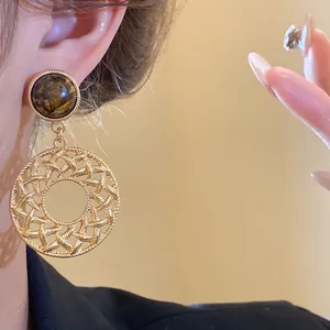 Close-up detail view of elegant retro Tiger's Eye stone hollow round golden dangle earrings