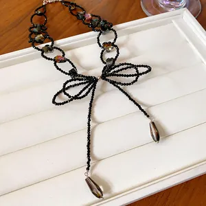 Macro di una collana con pendente a fiocco in perle nere e accenti a stella.