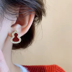 A detailed view showing a red enamel wulu gourd stud earring with zircon on the ear