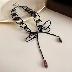 Primo piano della collana choker a perline nere con fiocco e pendenti in cristallo.