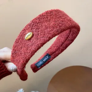 Close-up view of a wine red fuzzy wide headband showing the KOREA gold metal tag detail.