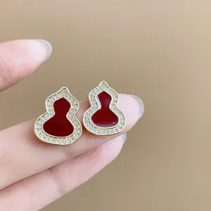 Detailed macro view of elegant red gourd stud earrings with sparkling zircon borders.