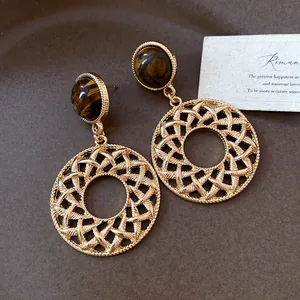 Macro detail view of vintage tiger eye stone earrings with intricate hollow round pendants