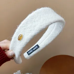 Close-up of white flocked wide headband showing soft fuzzy texture and gold button.