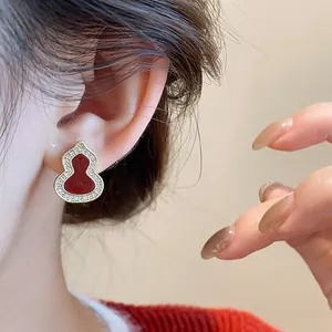 Close-up view of elegant red enamel gourd stud earrings with zircon-set gold frame