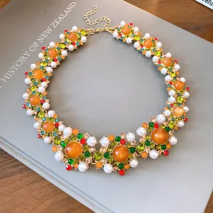 Detailed macro view of a vintage court style necklace with orange gems and white pearls.