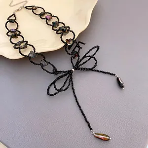 Primo piano di un elegante collana di perline stile dark con fiocco e ciondoli iridescenti