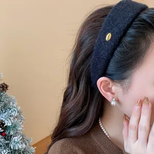 Detail view of a chic black flocked wide headband featuring a gold metal Korea tag