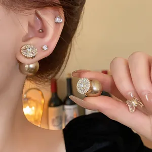Detailed close-up of gold-plated zircon and pearl double-sided stud earrings