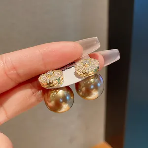 Close-up detail of champagne gold pearl earrings with shimmering zircon stud