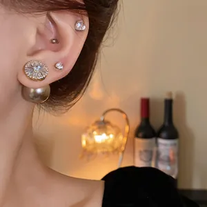 Detail view of gold-plated silver needle earrings with zircon and pearl accents