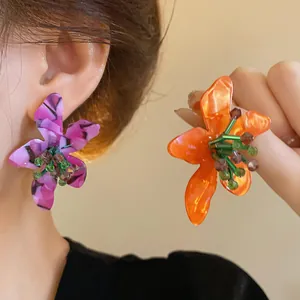 Detail of vibrant floral acetate earrings with beaded center in purple and orange.