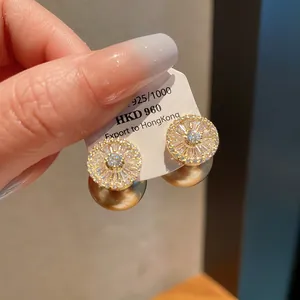 Detail of gold-plated stud earrings featuring brilliant CZ sunburst and pearl drops.