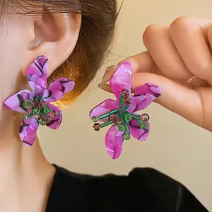 Purple marbled acetate flower earrings with green beaded center worn by a model