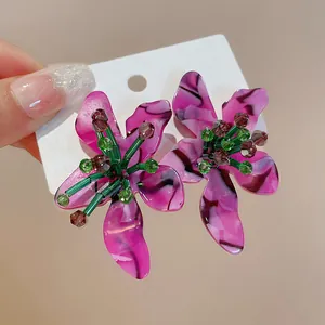 Close-up of pink marbled acetate flower earrings with green beaded stamens