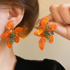 Close-up of vibrant orange acetate flower earrings with crystal bead details for summer.