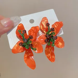 Detailed view of vibrant orange flower acetate earrings decorated with purple crystal beads