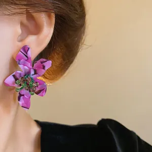 Detailed view of a purple acetate flower earring with green crystal beads