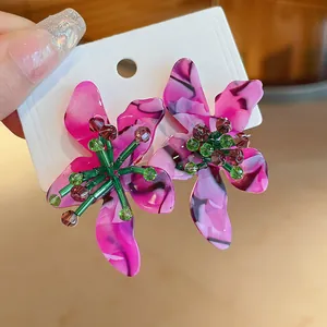 Detailed close-up of pink marbled acetate floral earrings with green beaded centers