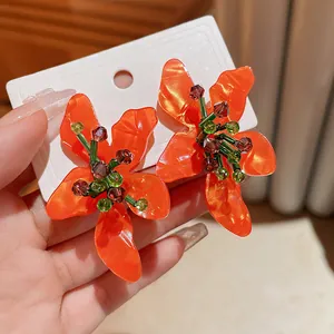 Detailed close-up view of orange floral acetate earrings featuring green and purple crystals