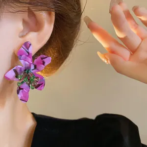 Exquisite purple acetate flower stud earrings with sparkling crystal center worn on ear