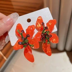 Detailed macro shot of orange flower earrings crafted from acetate with crystals