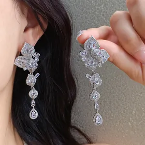 Close-up view of elegant sparkling zirconia leaf tassel earrings worn by a model.