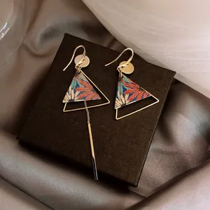 Detail view of asymmetric ethnic earrings with colorful floral pattern and golden metal finish