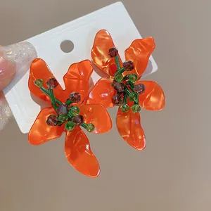 Macro view of vibrant orange acetate flower earrings with intricate crystal bead detailing