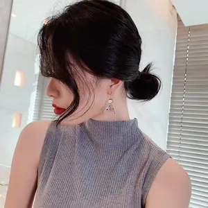 Macro close-up of ethnic style triangular earrings on an Asian model with gold hooks