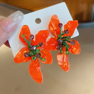 Close-up of vibrant orange flower earrings with crystal bead details on white card
