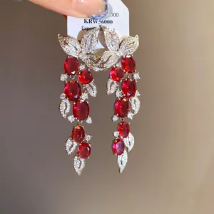 Macro view of elegant leaf tassel earrings featuring vibrant red stones and zircons
