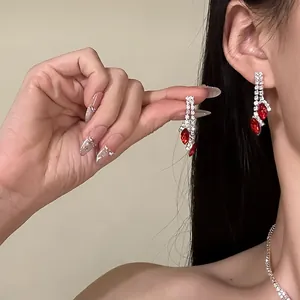 Gros plan détaillé montrant le design complexe en strass et pierres rouges des boucles d'oreilles