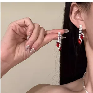 Parure boucles d'oreilles et collier à strass avec pierres rouges portée sur mannequin.