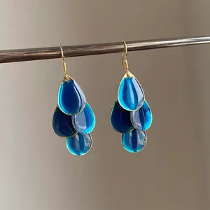 Close-up detail of layered blue teardrop enamel earrings with elegant gold hooks