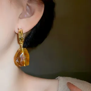 Close-up of vintage irregular amber earrings worn on model's ear