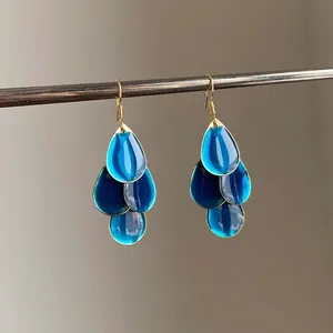 Detailed macro view of retro style blue enamel waterdrop tassel earrings with golden hooks