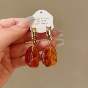 Close-up of vintage Maillard style earrings with irregular amber resin drops