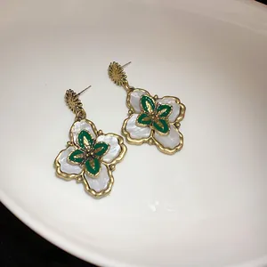 Close-up detail of vintage court style flower earrings with green enamel and white petals