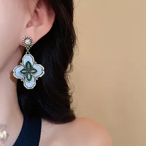 Close-up view of vintage court style flower earrings with green and blue enamel