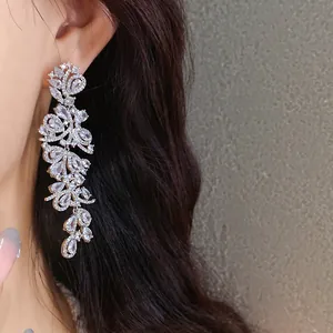 Detail view of sparkling cubic zirconia leaf tassel earrings worn on a model's ear