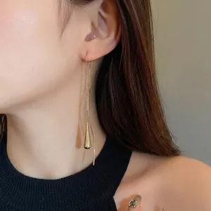 Elegant minimalist gold metal teardrop tassel geometric ear wire earrings worn by model