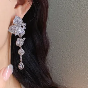 Detailed macro shot of elegant silver-colored zircon leaf tassel earrings on a model