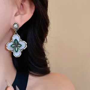 Close-up of vintage palace style floral drop earrings with green enamel detail