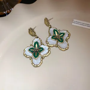Close-up macro view of vintage court-style floral earrings with green enamel inlay