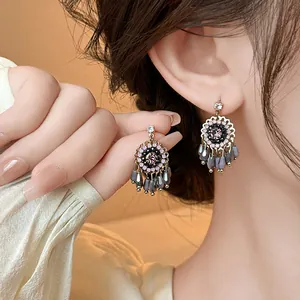 Detail view of vintage oil painting style earrings with pink crystals and grey beads