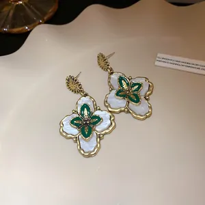 Detailed view of vintage palace style flower earrings with gold and green enamel finish.