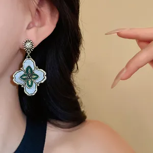 Close-up of a vintage court style flower earring with green and pearl inlay detail.