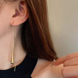 Close-up detail of a minimalist gold water drop tassel earring on a female model.